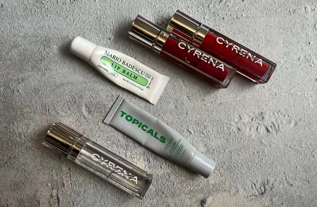 Flat lay of lip glosses, balms, and lipstick on a chic vanity with soft lighting