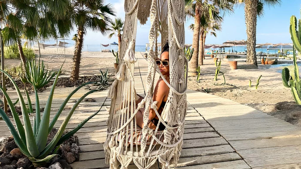 Black woman relaxing on a beach with glowing skin and a calm vibe